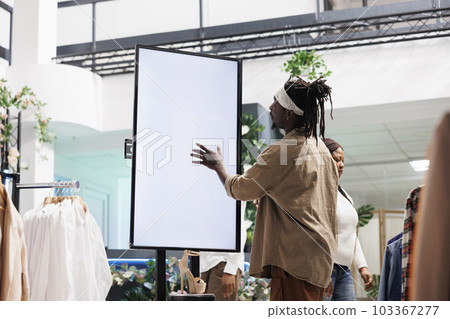 Customer interacting with digital smart board in clothing retail store. African american man tapping on whiteboard blank screen to read information about shoes new collection in shopping mall 103367277