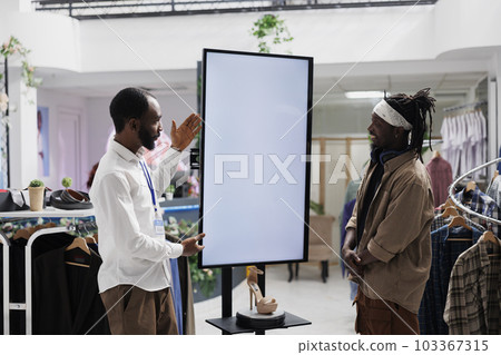 Mall employee advertising shoes brand to buyer, showcasing brand new collection on empty digital whiteboard mock up. Store assistant showing stiletto to customer on interactive display Mall employee advertising shoes brand to buyer, showcasing brand new collection on empty digital whiteboard mock up. Store assistant showing stiletto to customer on interactive display 103367315