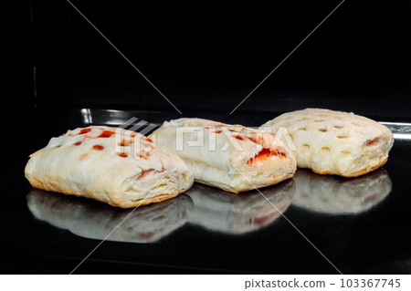 Three homemade buns with red strawberry jam baking in electric oven Three homemade buns with red strawberry jam baking in electric oven 103367745