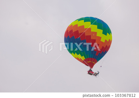 Colorful hot air balloon flying against grey sky at Winter aerostat festival 103367812