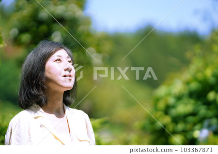 A middle-aged woman with a real face standing in the garden A middle-aged woman with a real face standing in the garden 103367871