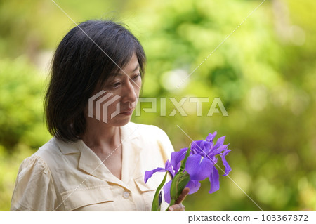 A middle-aged woman with a real face standing with flowers A middle-aged woman with a real face standing with flowers 103367872