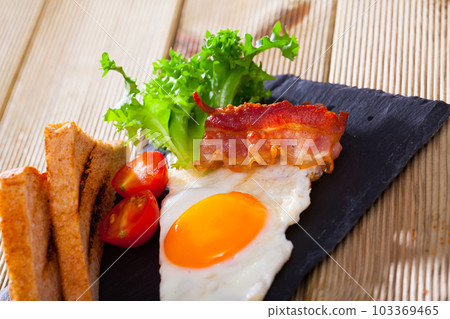 Fried egg with bacon and toasts Fried egg with bacon and toasts 103369465