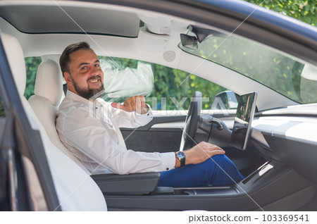 Caucasian bearded man in a suit driving a car.  103369541