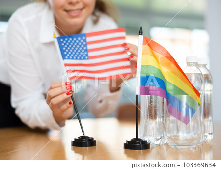 Young woman puts flags of Russia and Spain on table in office 103369634