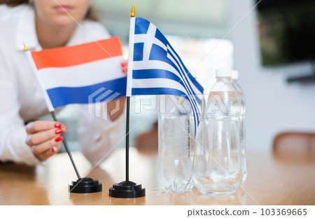 Unrecognizable girl sets midget flags of Greece and Netherlands before international negotiations Unrecognizable girl sets midget flags of Greece and Netherlands before international negotiations 103369665