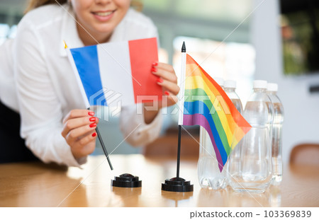 Unrecognizable girl sets midget flags of LGBT and France before international negotiations 103369839