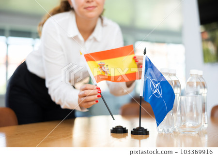 Businesswoman arranging the flags of NATO (OTAN) and Spain for presentation and negotiations 103369916