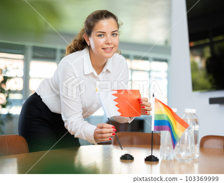 Young lady sets miniatures flags of LGBT and Bahrein before international negotiations 103369999
