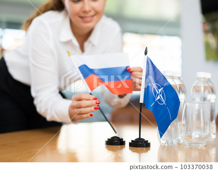 Young female secretary preparing room for international negotiations between nato and russia 103370038