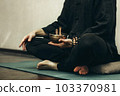 man sits with his legs folded and holding a copper singing bowl with sticks in his hands. Relaxation and meditation. Alternative medicine tibetan singing bowls 103370981