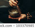 Close-up of hands with rosary playing on singing bowls. Relaxation and meditation. Alternative medicine. Tibetan and Himalayan singing bowls. Make a sound. 103370985