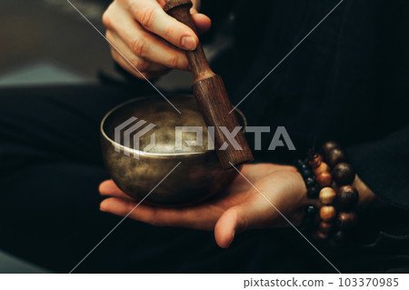 Close-up of hands with rosary playing on singing bowls. Relaxation and meditation. Alternative medicine. Tibetan and Himalayan singing bowls. Make a sound. 103370985