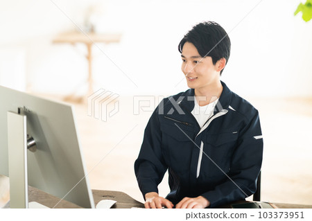 A young male engineer looking at a computer in work clothes A young male engineer looking at a computer in work clothes 103373951