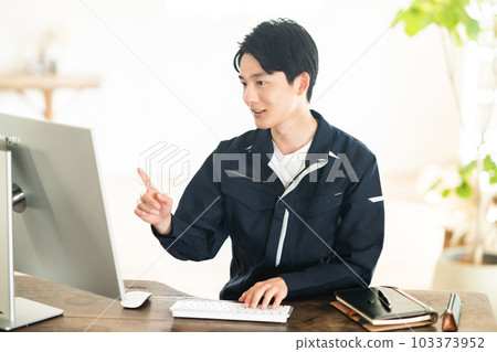 A young male engineer looking at a computer in work clothes 103373952