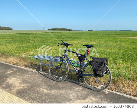 Bicycle with a bike frame bag and pannier bags on the background of open space of the countryside. Concept of travel by bike, active and sporty lifestyle Bicycle with a bike frame bag and pannier bags on the background of open space of the countryside. Concept of travel by bike, active and sporty lifestyle 103374808