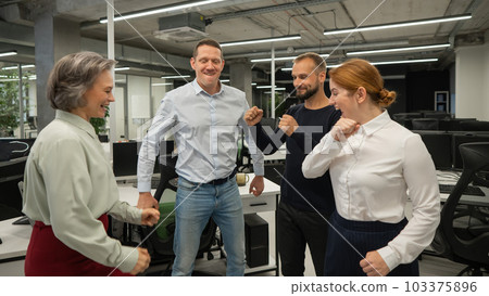 Four colleagues give the low five in the office. Four colleagues give the low five in the office. 103375896