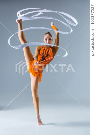 teenager doing gymnastics dance with white ribbon on a blue back 103377527