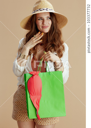 happy elegant woman in blouse and shorts against beige 103377732