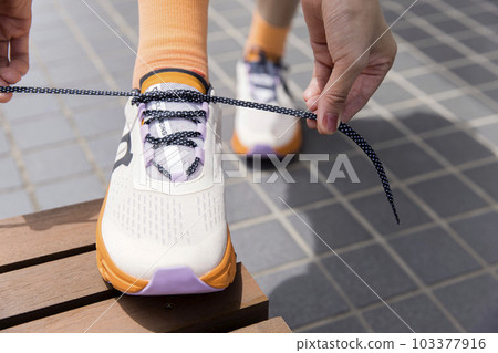 Female feet tying shoelaces of running shoes Female feet tying shoelaces of running shoes 103377916