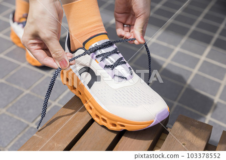 Female feet tying shoelaces of running shoes Female feet tying shoelaces of running shoes 103378552