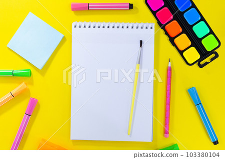 Back to school, drawing. Notebook checkered with brush and pencil for notes to text. Near pink, orange, green stationery. Markers, felt-tip pens, sticky note. Concept of learning. Copy space 103380104