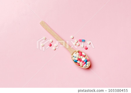 Vitamin capsules in a wooden spoon on a colored background. Pills served as a healthy meal. Drugs, pharmacy, medicine or medical healthycare concept 103380455