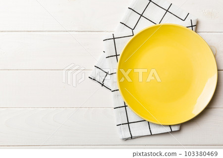 Top view on colored background empty round yellow plate on tablecloth for food. Empty dish on napkin with space for your design 103380469