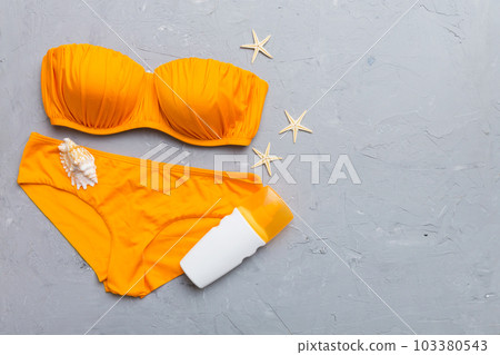 Woman swimwear and beach accessories flat lay top view on colored background Summer travel concept. bikini swimsuit, straw hat and seasheels. Copy space Top view 103380543