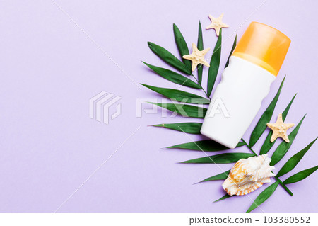 Sunscreen spray bottle. Bottle with sun protection cream and sea shells with tropical green leaf on color background, top view Sunscreen spray bottle. Bottle with sun protection cream and sea shells with tropical green leaf on color background, top view 103380552
