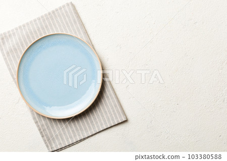 Top view on colored background empty round blue plate on tablecloth for food. Empty dish on napkin with space for your design 103380588