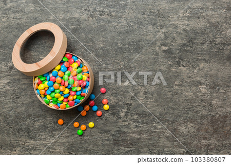 Set of different sweet candy in a paper box with a satin ribbon on a colored background. Holiday concept Set of different sweet candy in a paper box with a satin ribbon on a colored background. Holiday concept 103380807