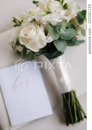 Wedding bouquet and vows on chair. White roses and eucalyptus. Beautiful fresh flowers. Bride morning concept Wedding bouquet and vows on chair. White roses and eucalyptus. Beautiful fresh flowers. Bride morning concept 103381159