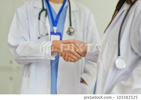Close up shot of two doctors shaking hands to each other. Healthcare, collaboration in medicine and teamwork Close up shot of two doctors shaking hands to each other. Healthcare, collaboration in medicine and teamwork 103381525