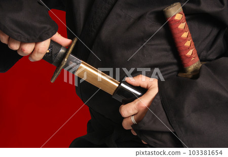 Man Removing Japanese Katana Blade From Scabbard Man Removing Japanese Katana Blade From Scabbard 103381654
