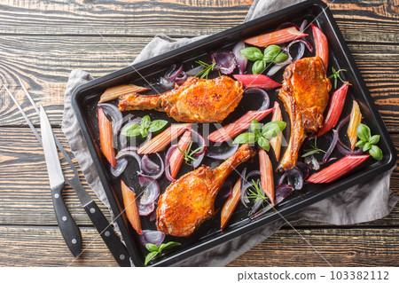 Baked pork chops with red onions, herbs and rhubarb in honey glaze close-up in a baking sheet. Horizontal top view Baked pork chops with red onions, herbs and rhubarb in honey glaze close-up in a baking sheet. Horizontal top view 103382112