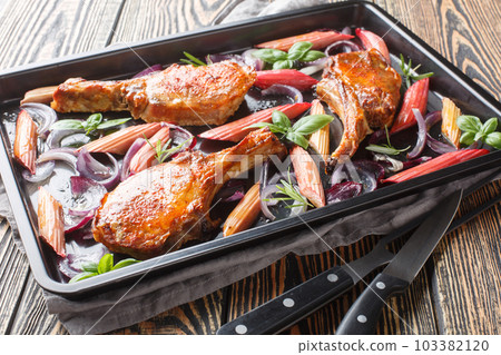 Healthy and tasty food baked pork chops with red onion, herbs and rhubarb close-up in a baking sheet. Horizontal 103382120