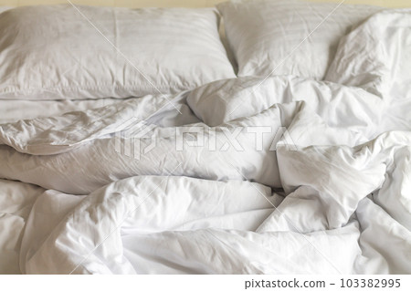 Crumpled messy unmade bed in hotel with pillows 103382995
