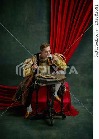 Young man in vintage clothing, royal person, princess sitting and drinking beer with wish against dark green, vintage background Young man in vintage clothing, royal person, princess sitting and drinking beer with wish against dark green, vintage background 103383081