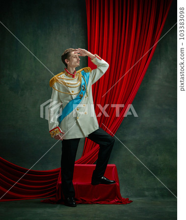 Portrait of young man, royal person, king, duke on elegant costume, standing with noble look against dark green, vintage background 103383098