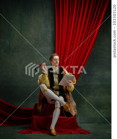 Portrait of young male royal person with thoughtful face looking in tablet and working against dark green, vintage background 103383120