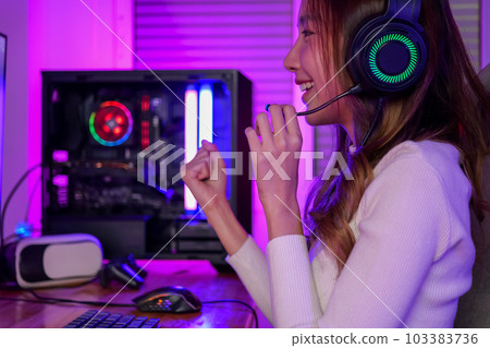 Young woman wearing headphones playing computer game 103383736