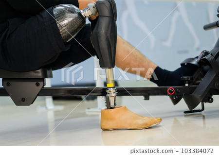Disabled sporty man exercising with prosthetic leg at gym 103384072