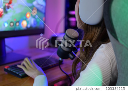 Young female game streamer playing online game on computer at home Young female game streamer playing online game on computer at home 103384215