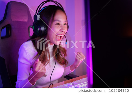 Young woman wearing headphones playing computer game Young woman wearing headphones playing computer game 103384530