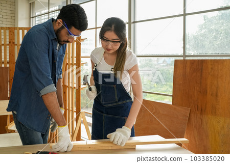 Female carpenter and male worker happy and making furniture in carpentry shop 103385020