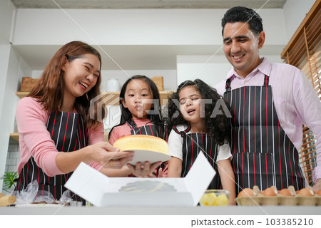 Child making cake with family, Family having fun together in kitchen Child making cake with family, Family having fun together in kitchen 103385210