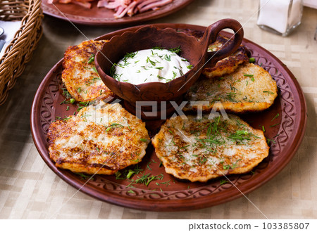 potato pancakes with sour cream and herbs on white plate 103385807