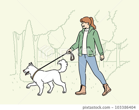 Smiling woman walking with dog in park  103386404