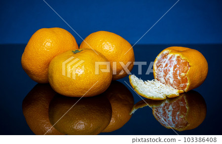 Heap ripe yellow tangerines or mandarins fruit on blue background. Idea clementines dieta. 103386408